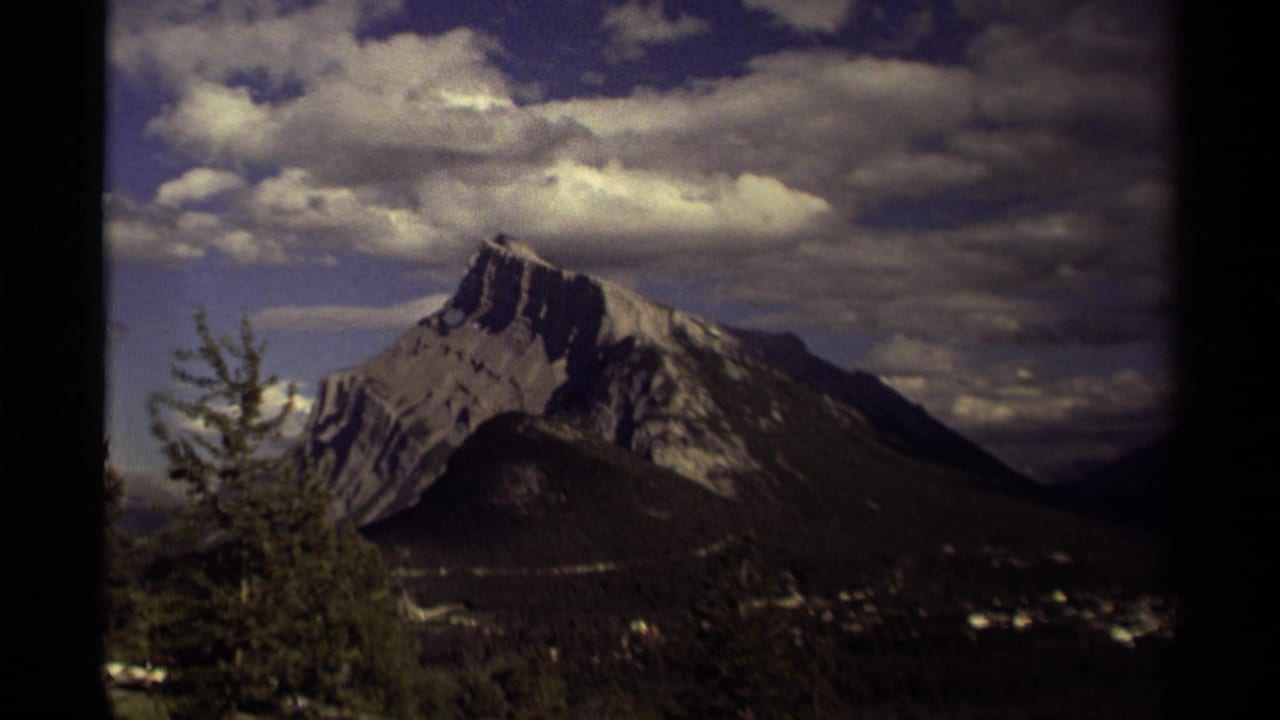 Rugged mountain peak above a valley under heavy clouds.