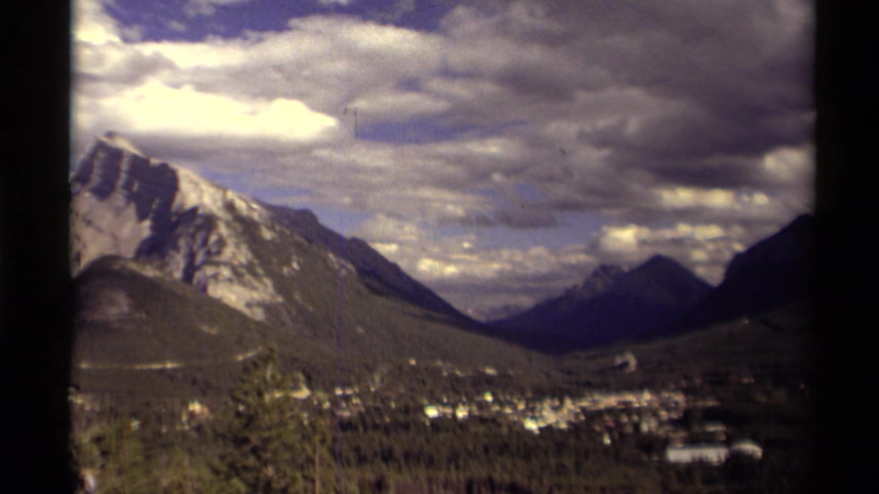 Mountain ridge and valley town viewed through dark window-frame edges.