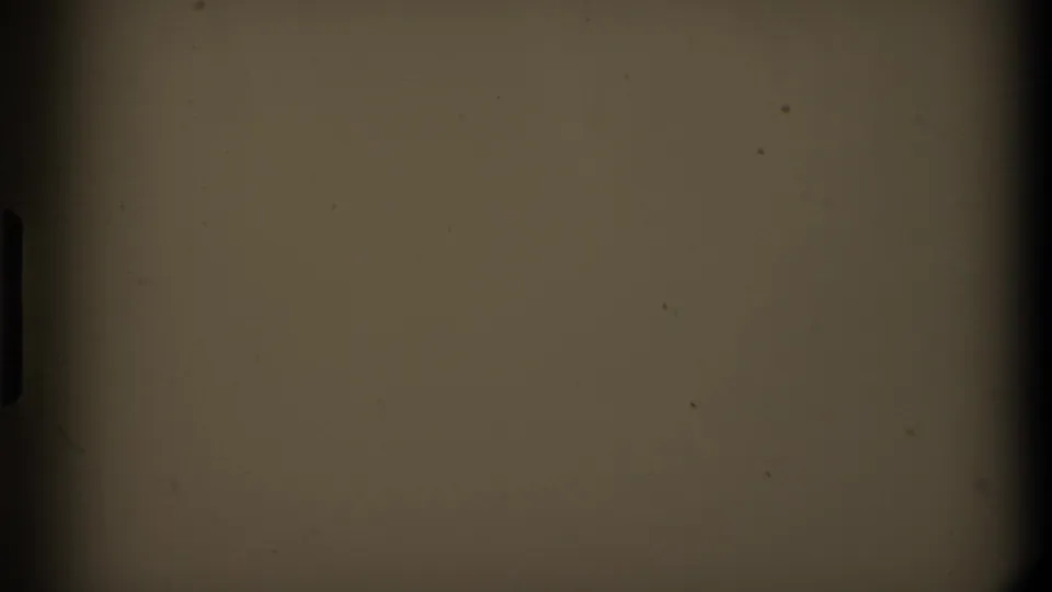 End frame from the 8mm scan showing a mostly blank warm-toned area with dark rounded film borders and small dust marks.