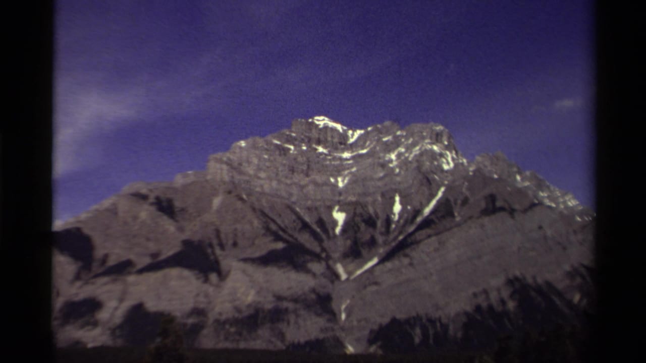 1979 Canadian 8mm view of rocky mountain peaks with bright snow patches and dark frame borders.