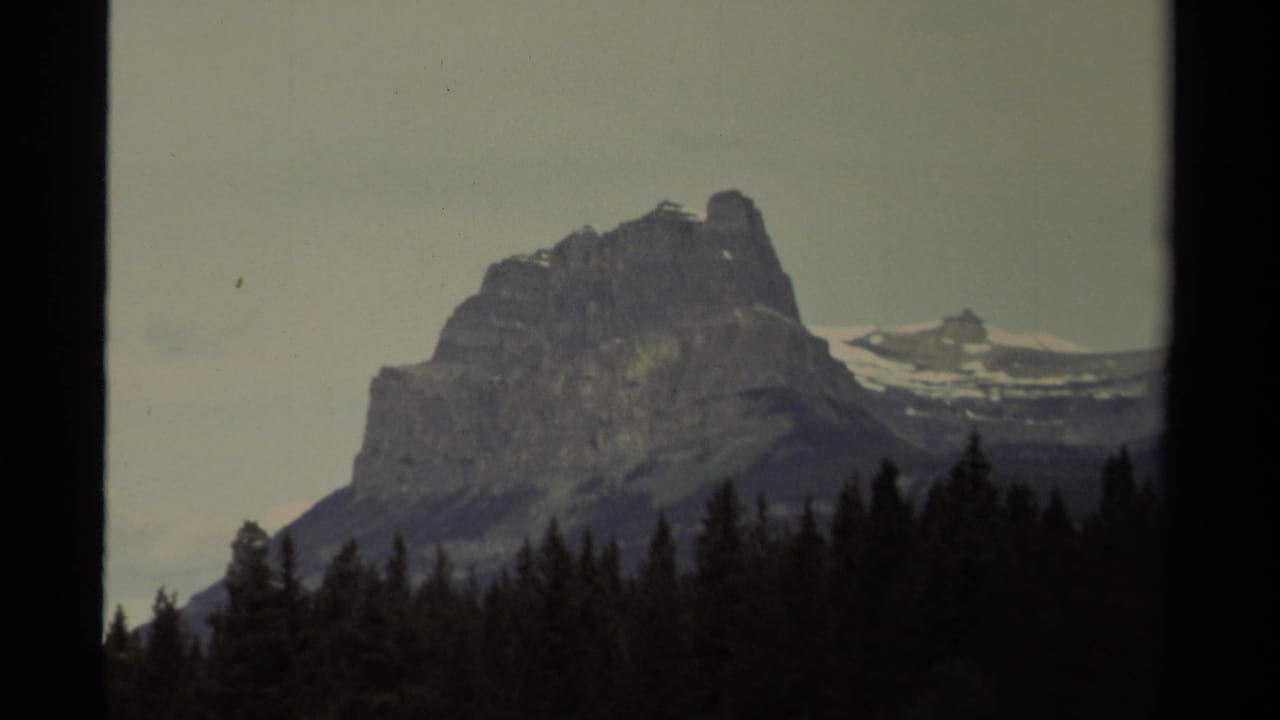 1979 Canadian 8mm frame holding on the mountain from a similar angle, with evergreen treetops across the lower frame.