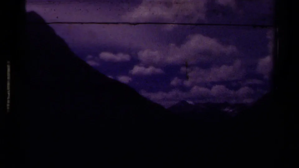 1979 Canada 8mm view of a dark mountain silhouette against a purple-blue sky filled with layered clouds.
