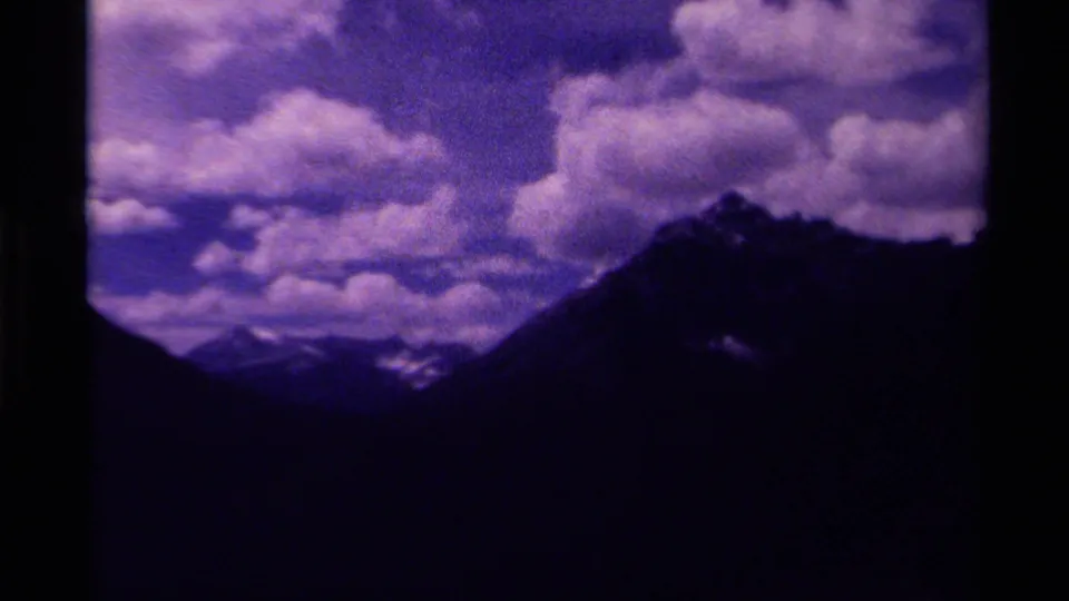 1979 Canadian 8mm frame showing silhouetted mountain peaks under billowing clouds with a strong purple-blue color cast.