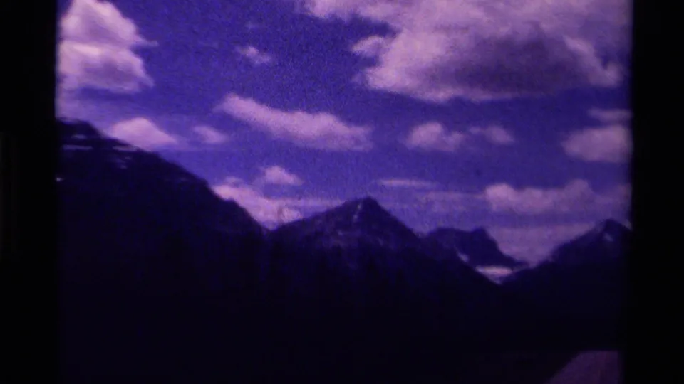 1979 Canada 8mm frame with shadowed mountain forms, bright cloud clusters, and visible film gate borders.