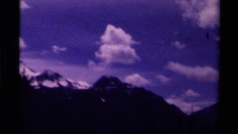 1979 Canada 8mm frame showing a snow-capped ridge line below a tall cloud, with strong purple-blue film coloration.