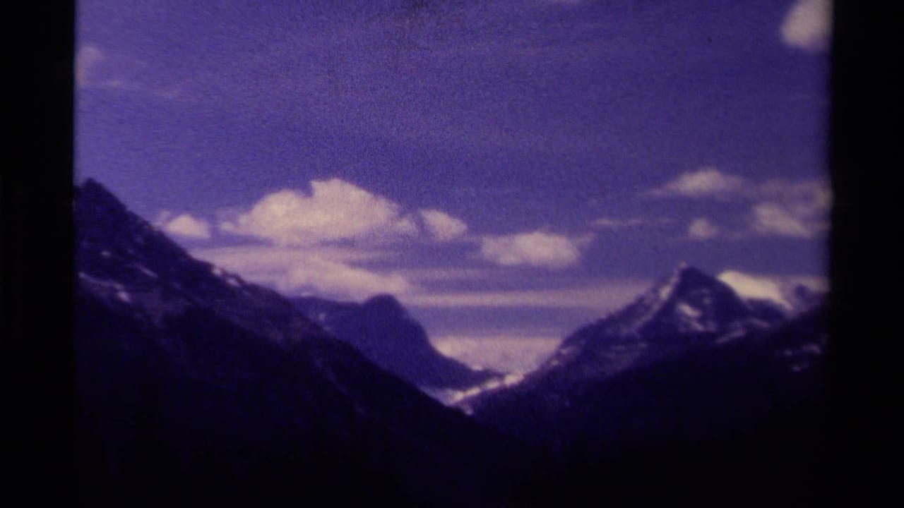 Snowy mountain peaks beneath a cloudy purple-blue sky.