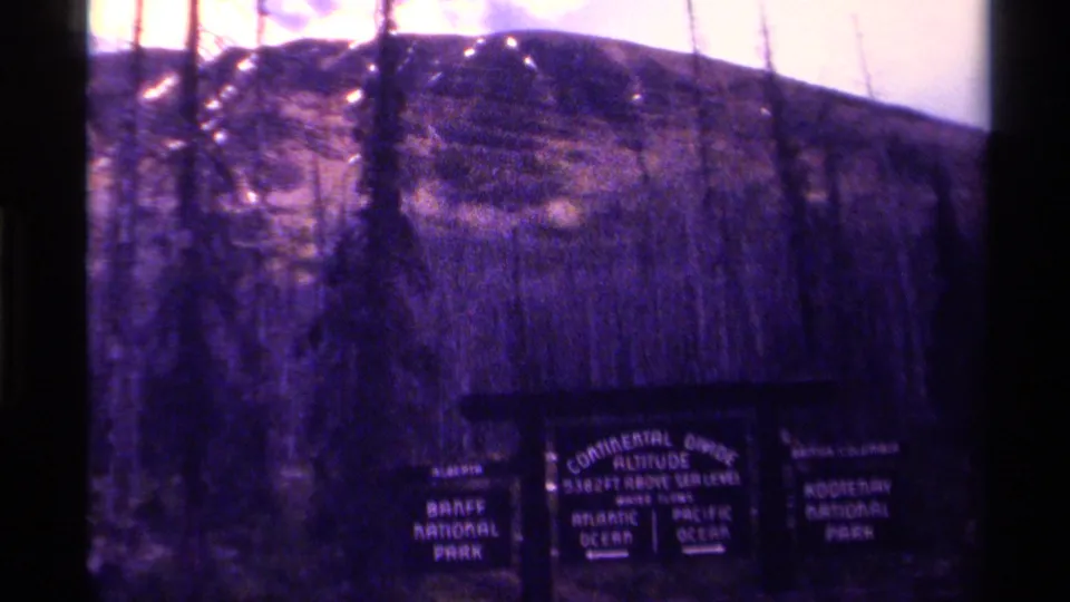 1979 Canada 8mm frame showing the upper portion of a Continental Divide sign between Banff and Kootenay park panels.