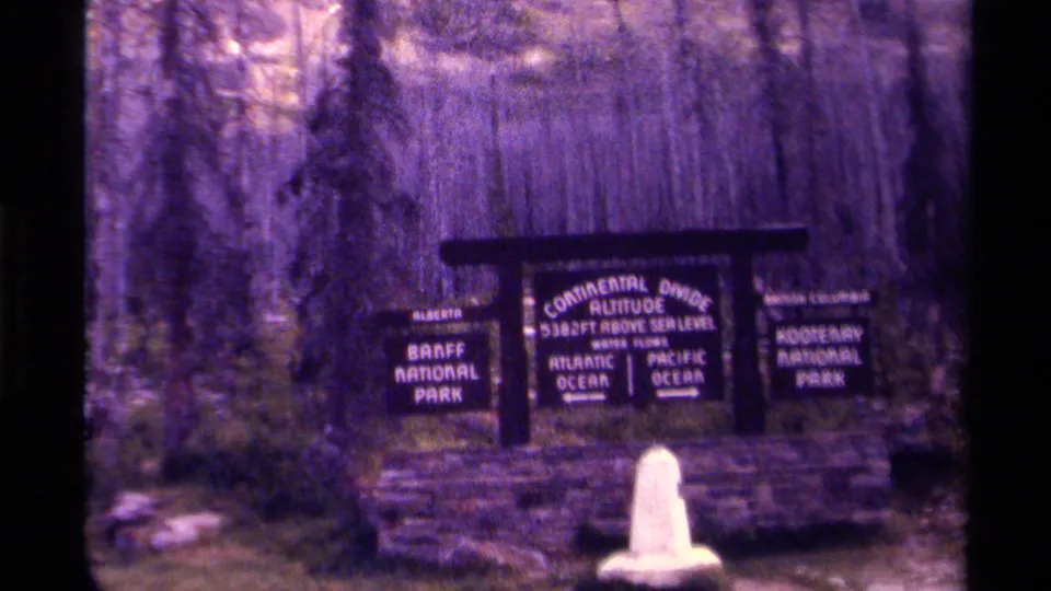 1979 Canada 8mm frame with the Continental Divide sign centered between Banff and Kootenay National Park panels.