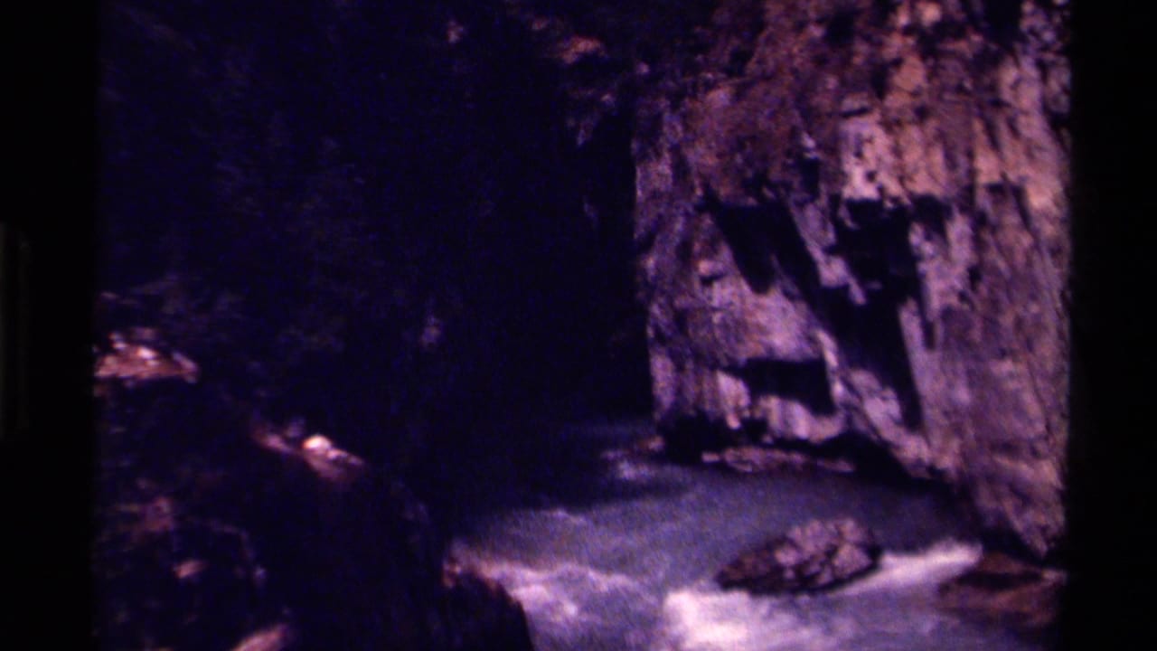1979 Canada 8mm view of pale rapids passing between dark canyon walls and a rough rock face.