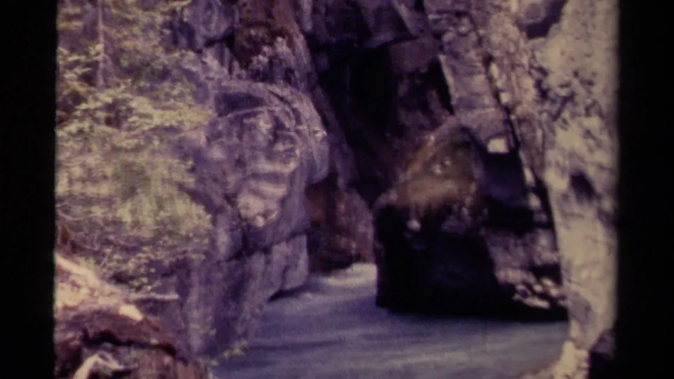 1979 Canadian 8mm frame showing a cave-like opening next to shallow water within a narrow rock corridor.