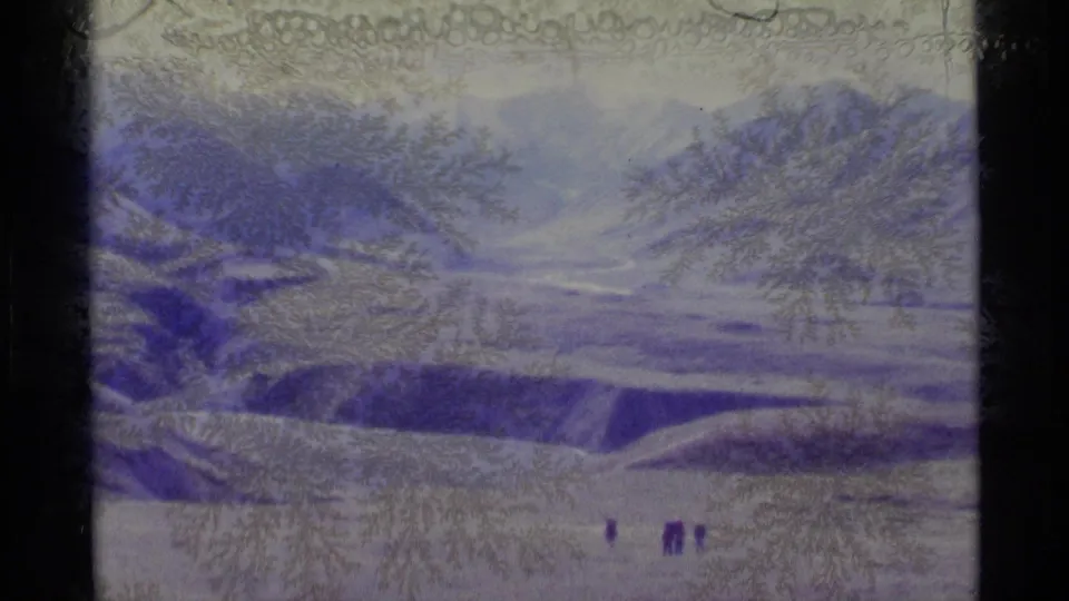 1977 Alaska 8mm frame showing a broad snowy valley, distant mountains, and tiny hikers under a pale sky with purple film cast.