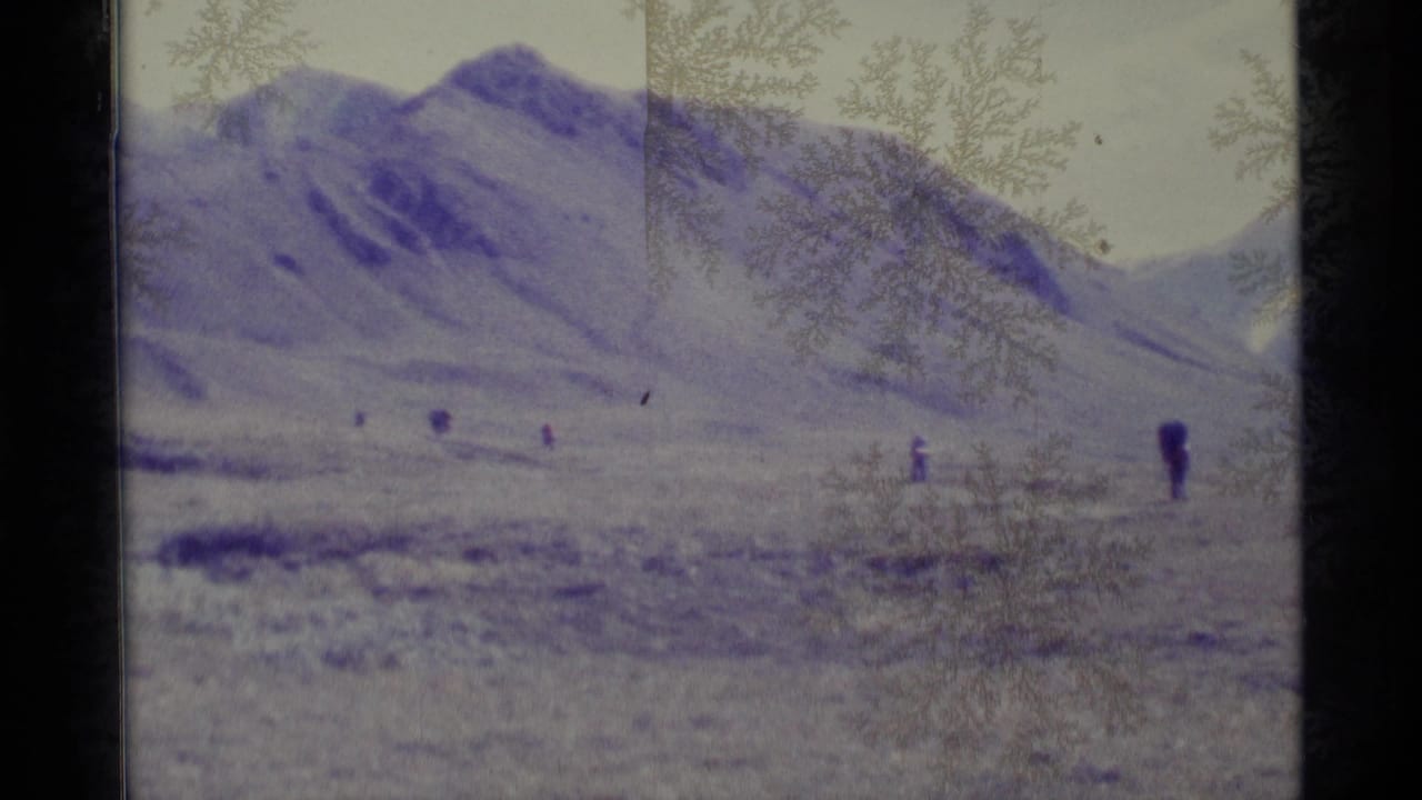 Wide mountain landscape with distant hikers and frost-like marks on the lens.
