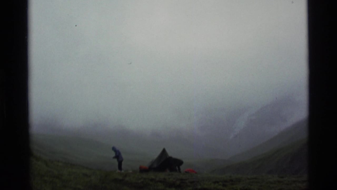 Small tent and standing figure in a foggy mountain valley.