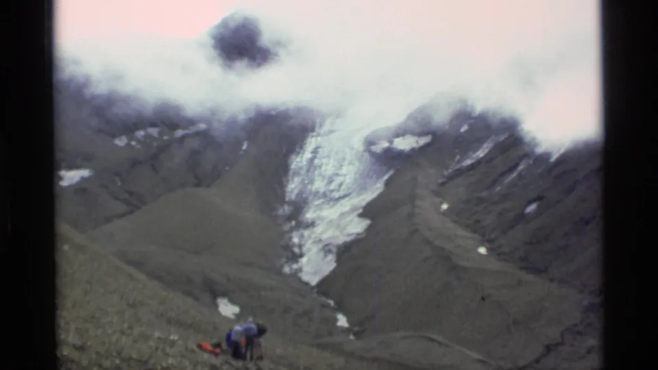 1977 Alaska home-movie view of glacier ice, snow patches, dark mountain slopes, and low cloud in a valley.