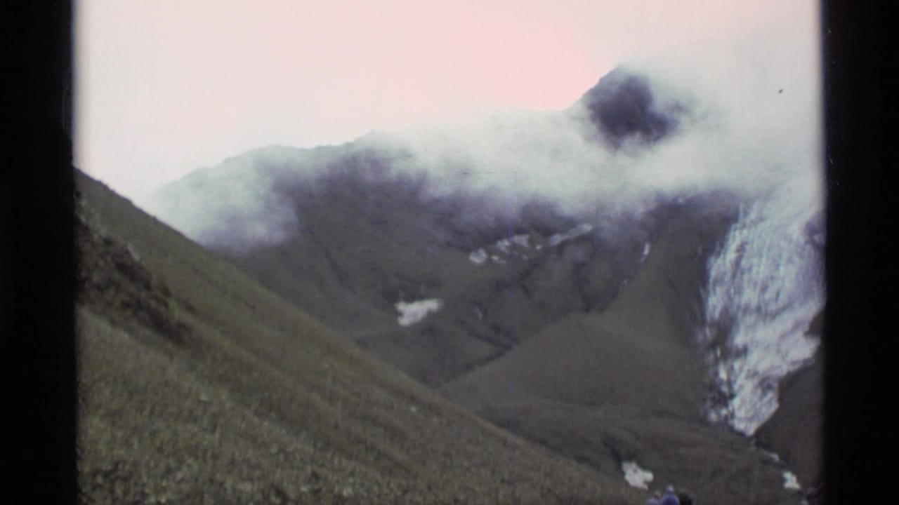 1977 Alaska 8mm frame showing fog over a dark mountain slope, with pale snow or ice visible at the right edge.