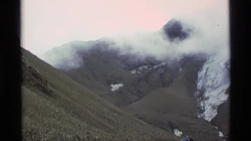 1977 Alaska 8mm frame showing fog over a dark mountain slope, with pale snow or ice visible at the right edge.