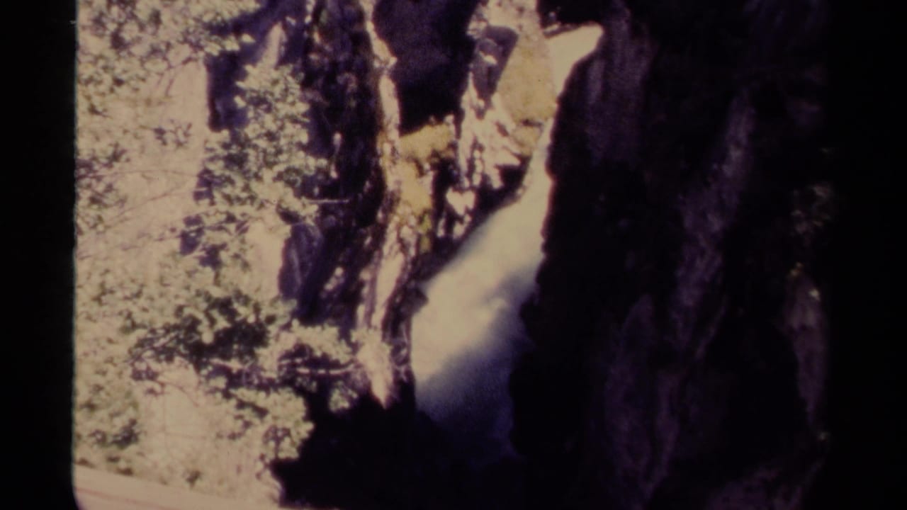 1979 Canadian 8mm view of water descending through a shaded canyon beside sunlit forest growth.
