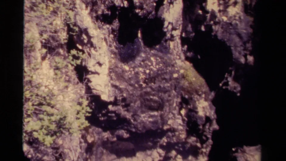 1979 Canadian 8mm frame showing a close, handheld view of rough rock beside a dark cavern opening.