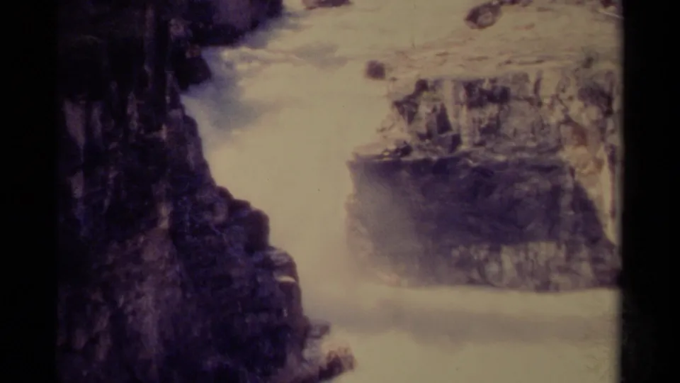1979 Canadian home-movie frame showing bright rushing water beside dark canyon rock, with softened grain and faded color.