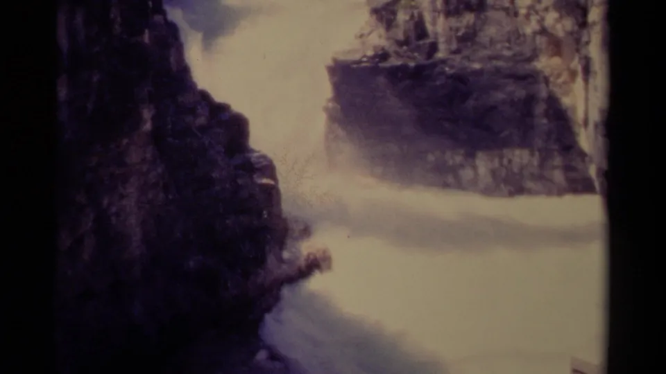 Vintage 8mm Canada frame of a powerful river flowing through a rocky canyon, with white spray and dark vertical stone walls.