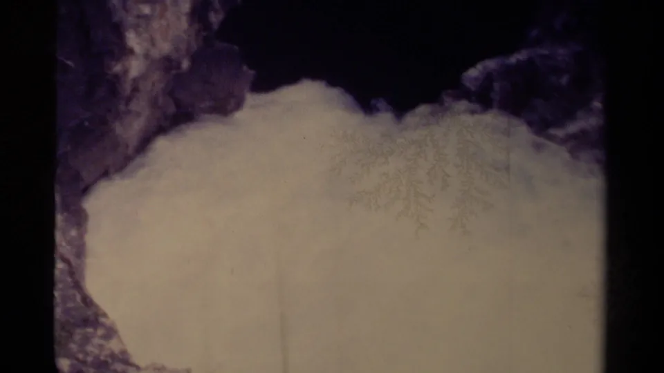 1979 Canadian 8mm view of a rounded snowbank framed by dark rock and faint winter branches.