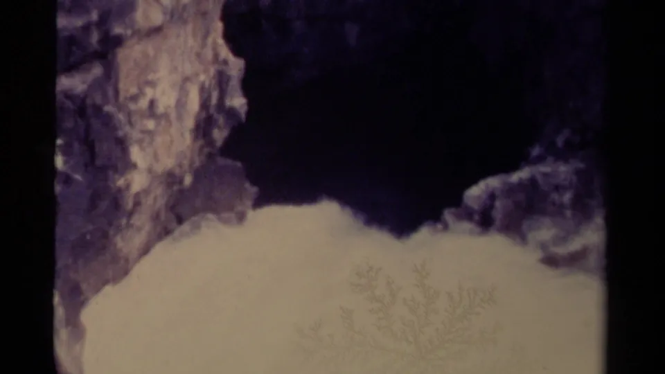 1979 Canadian 8mm frame with snow in the foreground, dark rock above, and rugged winter stone textures.