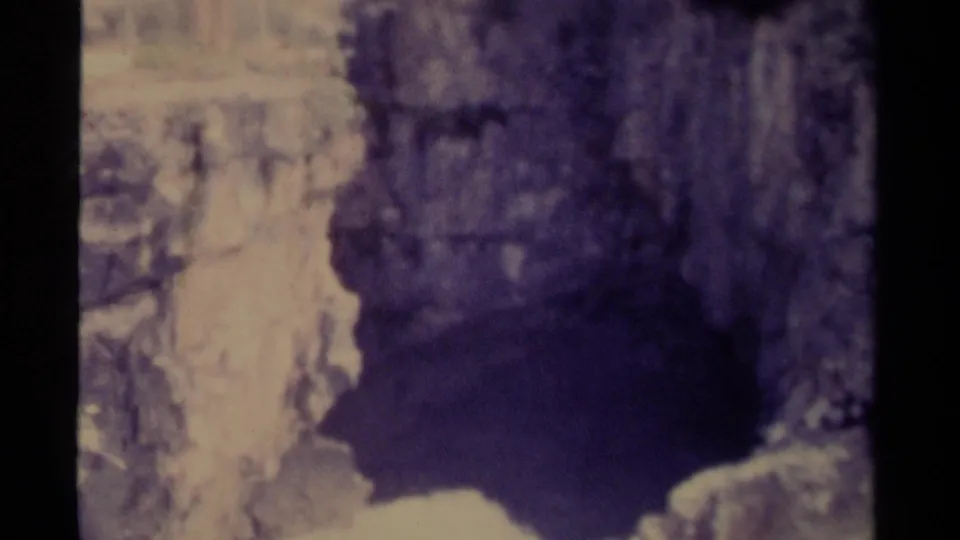 1979 Canadian 8mm frame showing a waterfall or icy cascade dropping between rocky walls above snow.