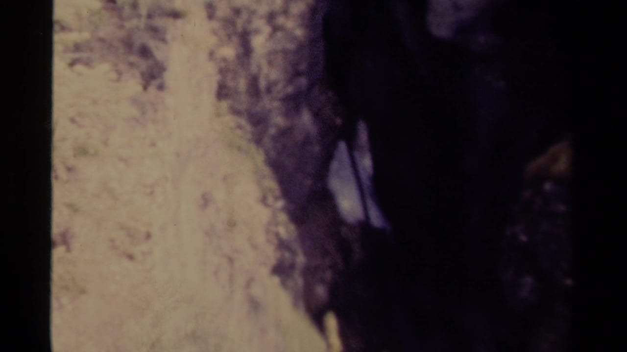 1979 Canadian 8mm frame showing fast water partly obscured by dark rock walls in a narrow natural channel.