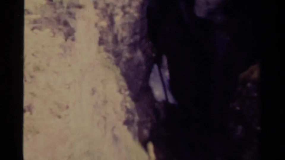 1979 Canadian 8mm frame showing fast water partly obscured by dark rock walls in a narrow natural channel.