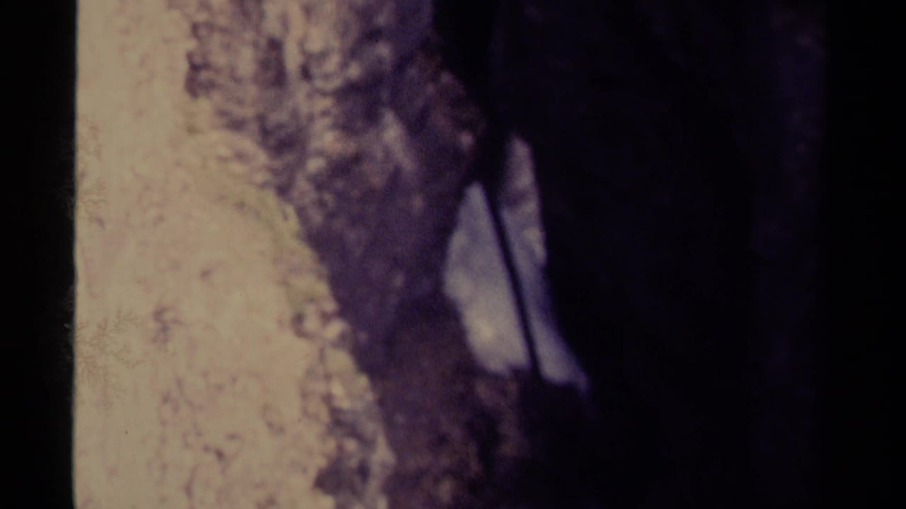 Vintage 8mm view of pale, fast-moving water passing along dark rocks in Canada, supported by clip metadata.