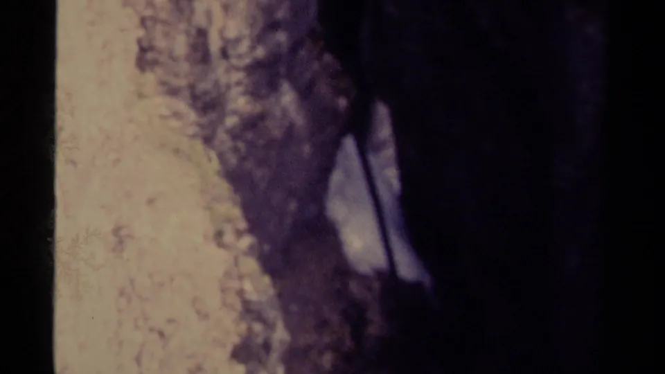Vintage 8mm view of pale, fast-moving water passing along dark rocks in Canada, supported by clip metadata.