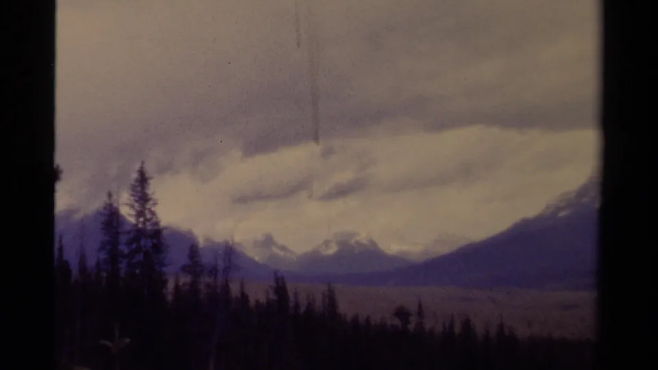 The final 1979 Canada frame holds on distant mountains, evergreen silhouettes, and a visible vertical scratch in the 8mm scan.