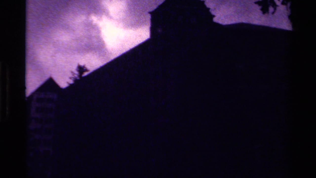 1979 Canada 8mm frame showing a large building partly in silhouette, with pine trees and a bright purple-shifted sky.