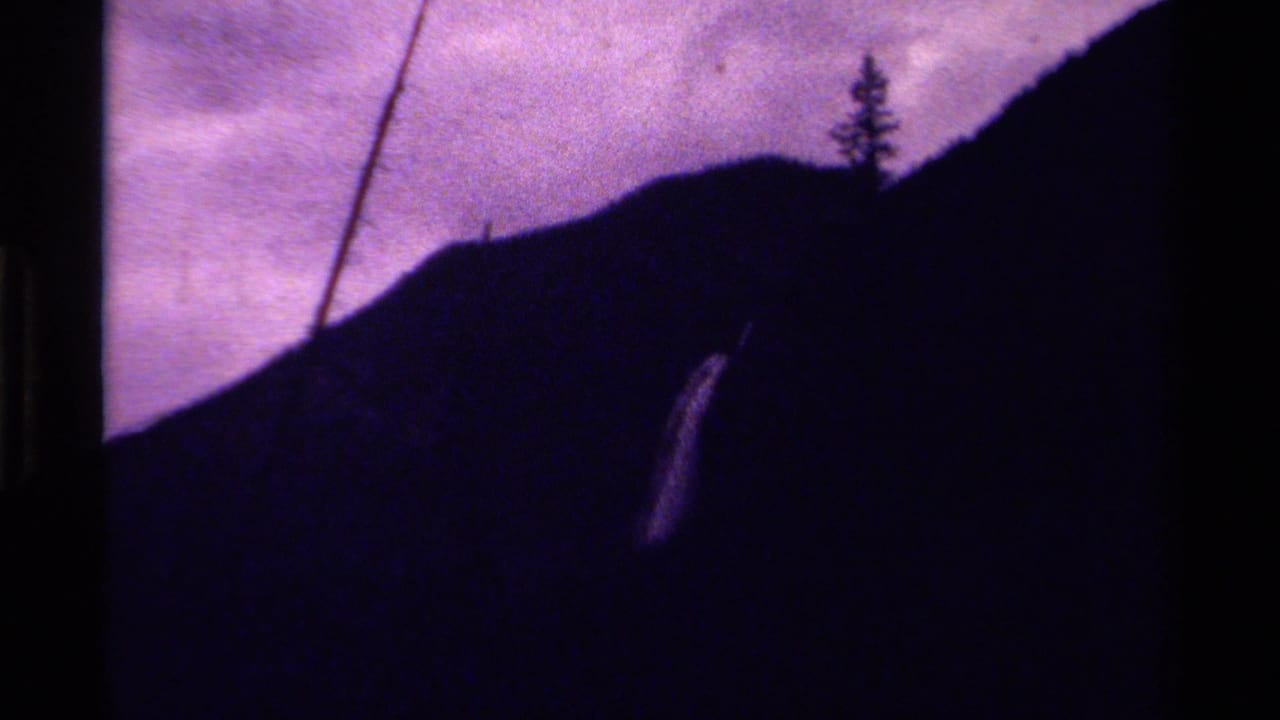 Dark mountain slope under a purple sky with a pale waterfall on the right.