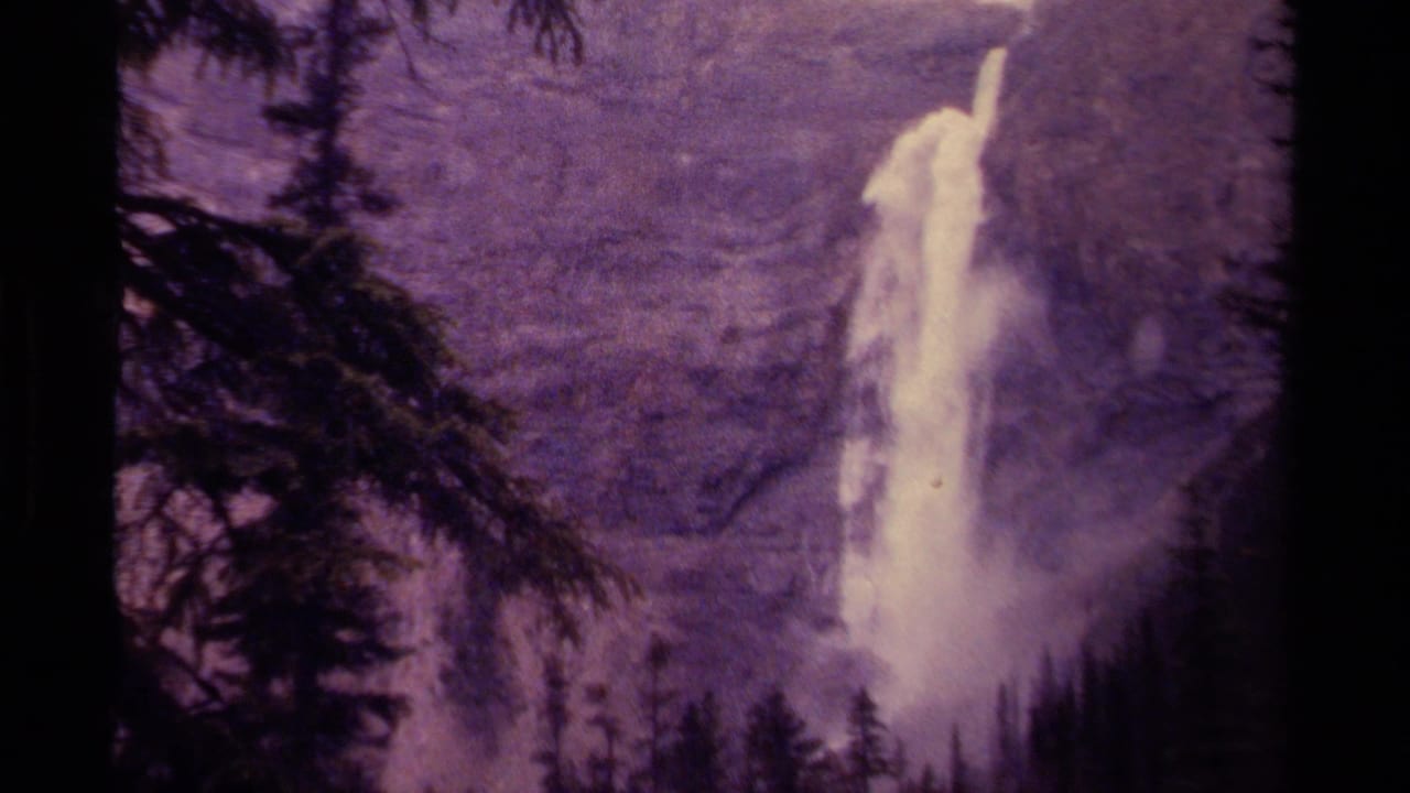 1979 Canadian 8mm view of a waterfall plunging down a mountain cliff, with forest silhouettes at the sides.