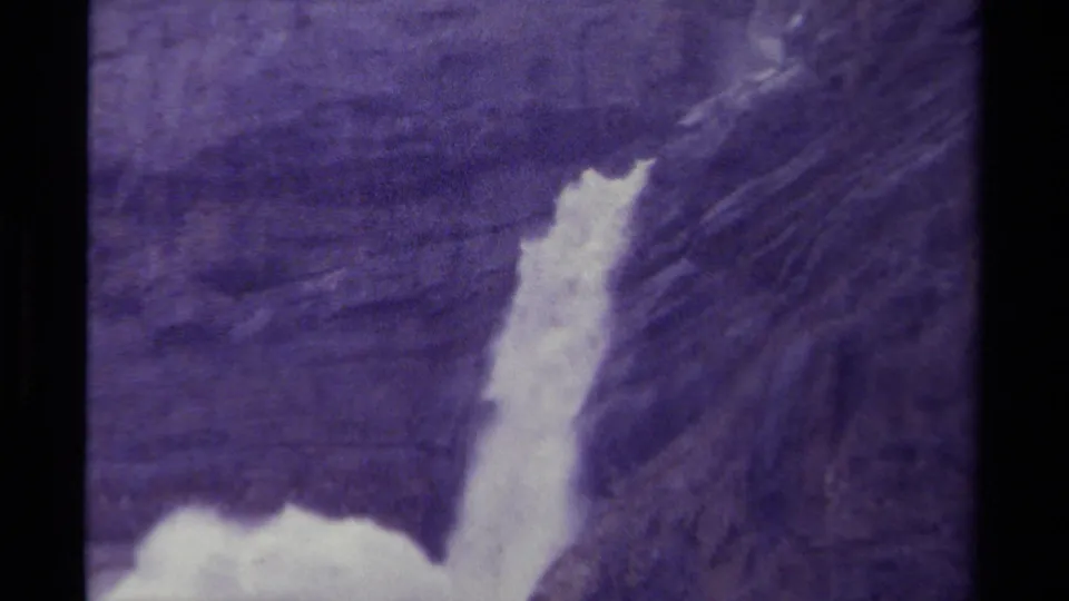 1979 Canadian 8mm frame with a brighter view of the waterfall beside a steep, textured rock face.