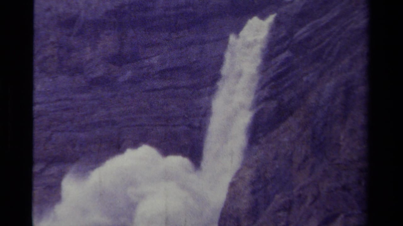 Waterfall dropping down a dark cliff with white spray at the lower edge.