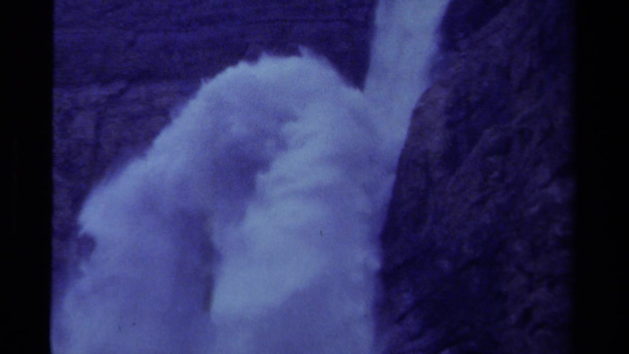 Blue-purple 8mm frame of a powerful Canadian waterfall pressing through a narrow rock channel.