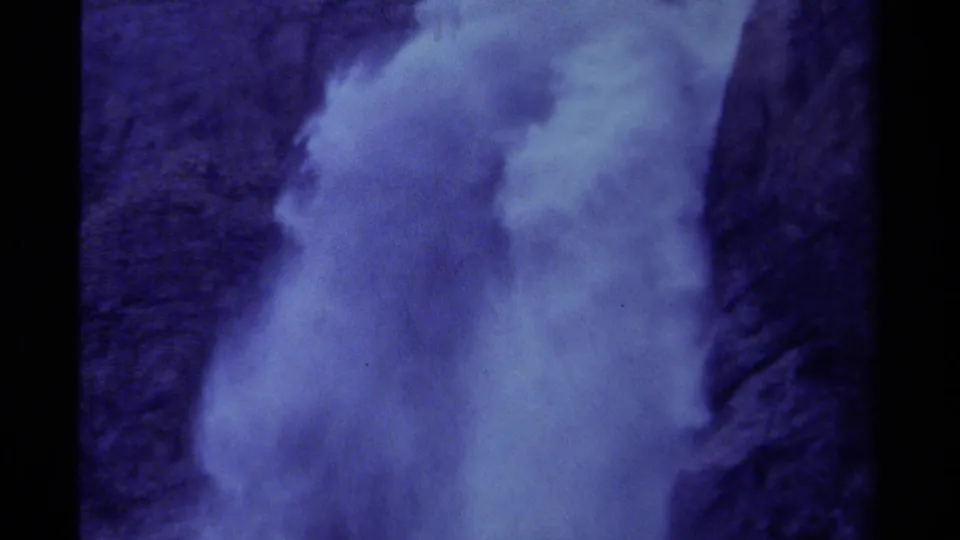 Vintage 8mm view of waterfall mist and spray swelling against a dark Canadian cliff face.