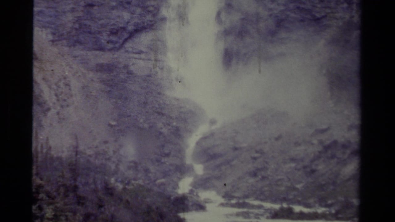 Waterfall dropping down a rocky mountain slope into a bright stream below.