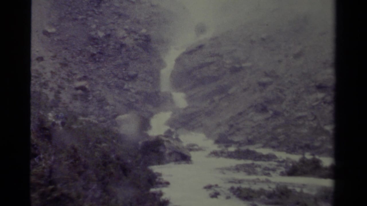 1979 Canada 8mm frame showing a swift whitewater river between rocky slopes in a rugged mountain valley.