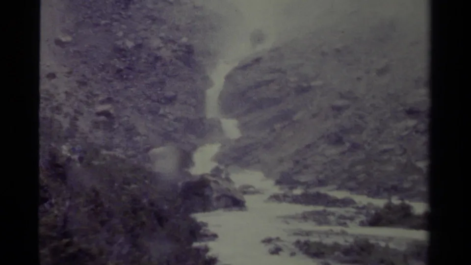 1979 Canada 8mm frame showing a swift whitewater river between rocky slopes in a rugged mountain valley.