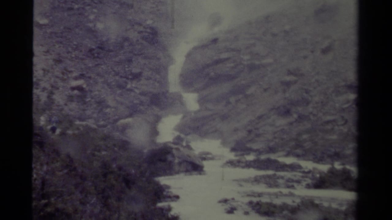 1979 Canada 8mm frame with bright, fast-moving water below rocky slopes and sparse vegetation.