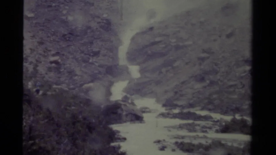 1979 Canada 8mm frame with bright, fast-moving water below rocky slopes and sparse vegetation.