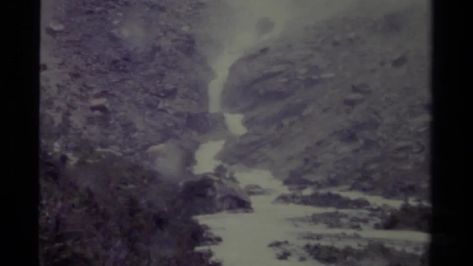 1979 Canada 8mm frame showing a soft, grainy view of a swift river bordered by rocks and brush.