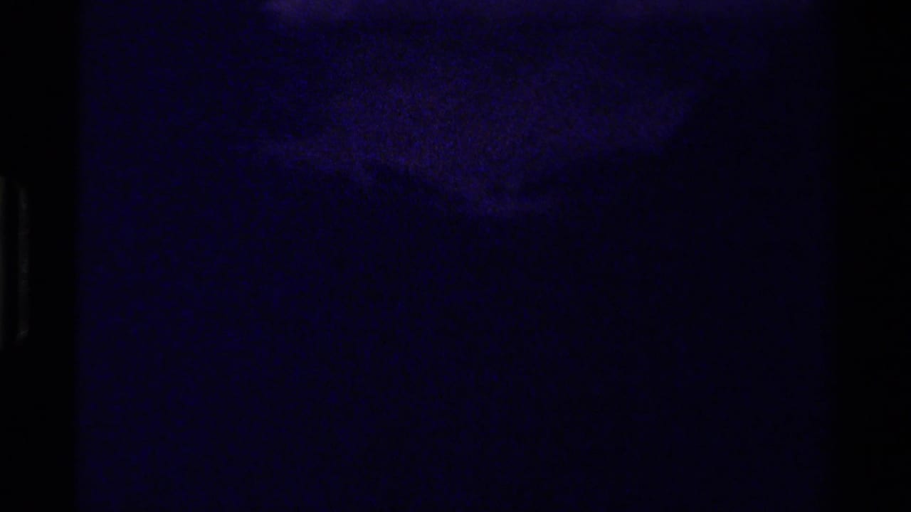 Very dark purple-tinted frame with indistinct forested mountain shapes.