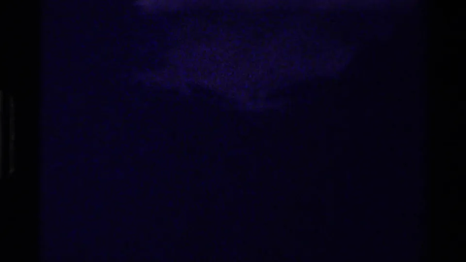 Dark, grainy 1979 8mm Canada travel frame with faint mountain and forest forms under a strong blue-purple cast.