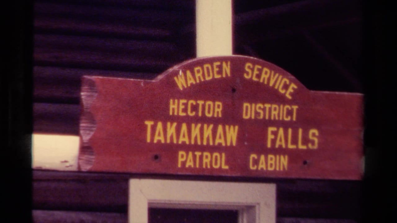 Red wooden Warden Service sign mounted above a cabin opening.