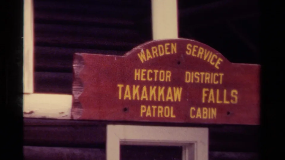1979 Canada 8mm frame showing the weathered wooden patrol cabin sign above white doorway trim on a log structure.