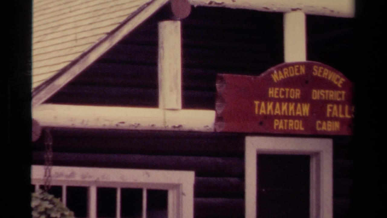 1979 8mm Canada frame showing the Takakkaw Falls Patrol Cabin sign, white-trimmed window, log wall, and doorway.